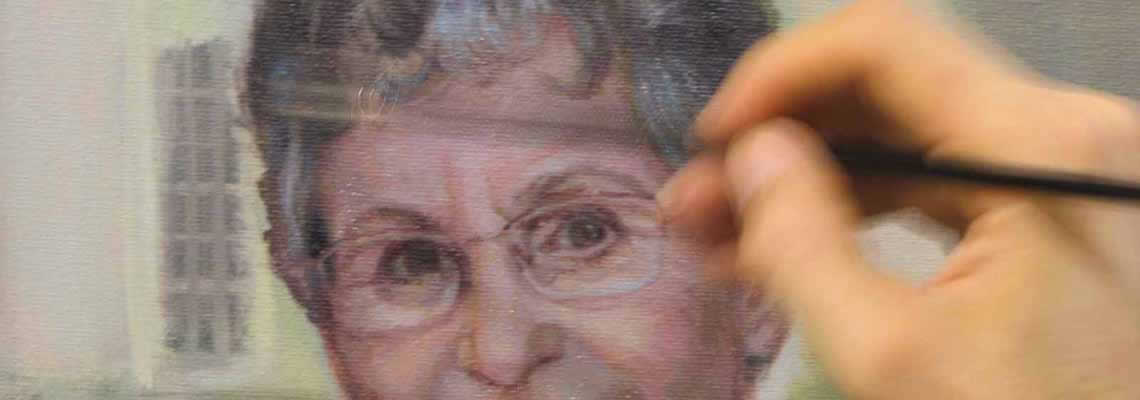 artist's hand paints details on the face of a portrait subject, Bobbie Bailey